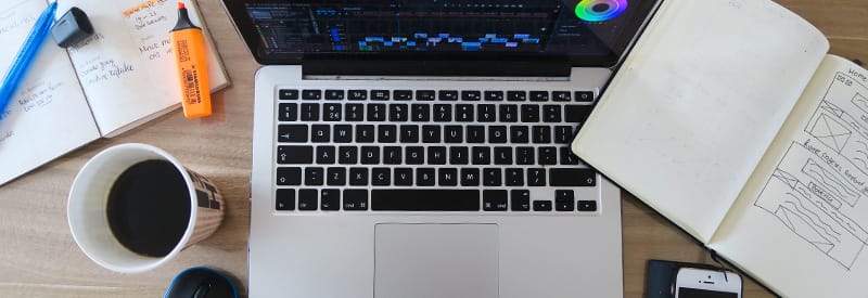 Notepad with highlighter on desk with laptop and other sketchbook